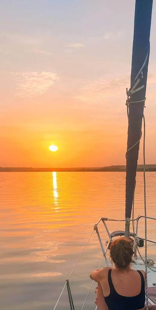 Marion Fournol regarde le coucher du soleil sur un voilier