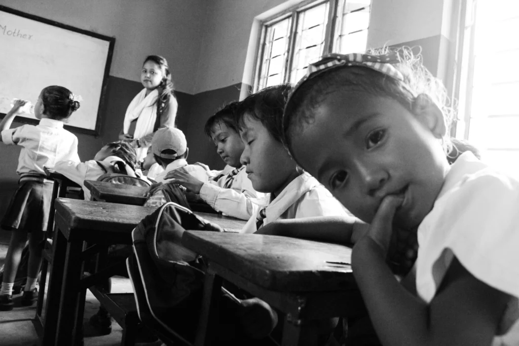 Une écolière en classe au Népal regarde la caméra 