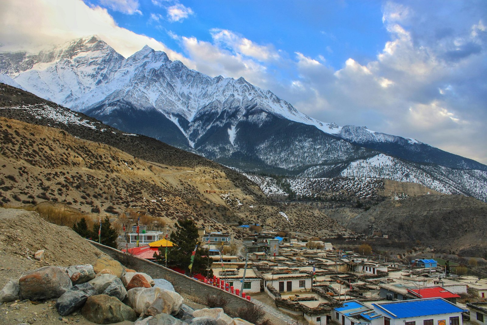 Captivating view of a Nepalese village nestled in the Himalayas beneath snow-capped peaks.